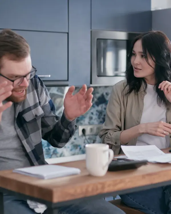 Casal discutindo à mesa da cozinha